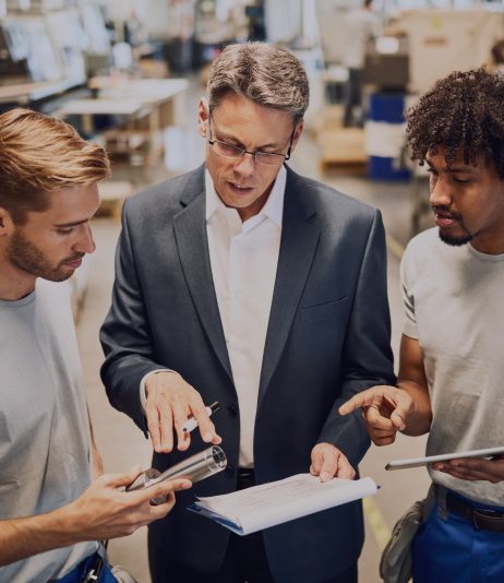 young-metal-workers-cooperating-with-their-manager-while-reading-reports-industrial-building 1